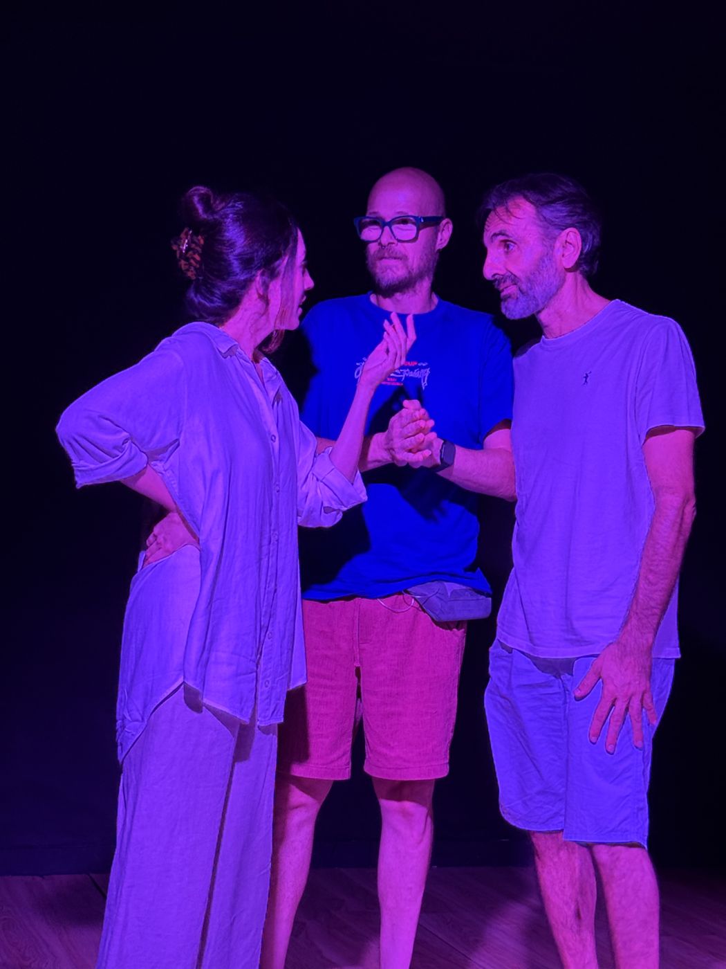 Tres compañeros del grupo de teatro conversan durante un ensayo